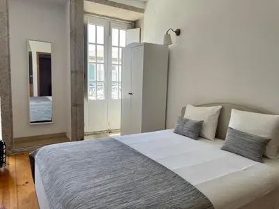 a white bedroom with a large bed with two pillows at Douro River Cozy Flats in Porto