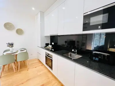 a white kitchen with a sink and a table at The Green House - Oporto Charming Apartment in Porto