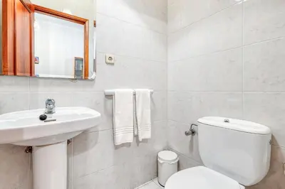 a white bathroom with a toilet and a sink at OPORTO GUEST Lobo Flat with Parking in Porto