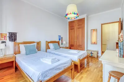 two beds in a room with white walls and wooden floors at OPORTO GUEST Lobo Flat with Parking in Porto