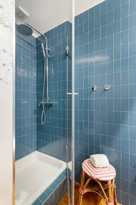 a blue tiled bathroom with a shower and a stool at Stylish Loft in the city centre in Porto