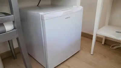 a small white refrigerator in a room at Bedroom with private bathroom in the city center, next to the subway in Porto
