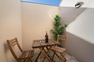 a table with a bottle of wine and two chairs at Host Wise - Central Private Flats - Terrace in Porto