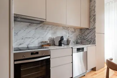 a kitchen with white appliances and marble walls at Stylish apartment in city center in Porto