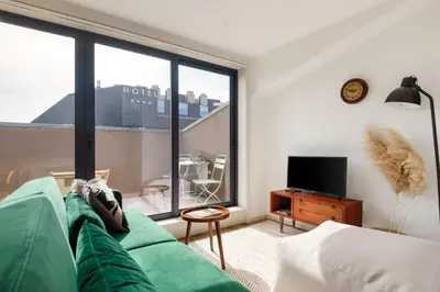 a living room with a green couch and a large window at Lovely 2-bed in the city centre with a sunny balcony in Porto