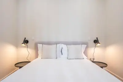 a bedroom with a large white bed with two lamps at Formosa Studio with Balcony by LovelyStay in Porto
