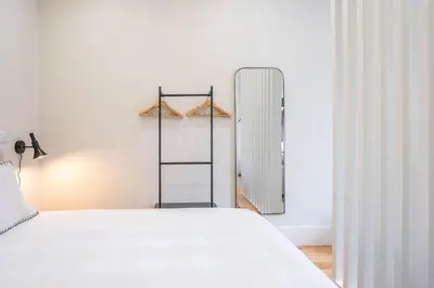 a bedroom with a white bed and a mirror at Formosa Studio with Balcony by LovelyStay in Porto