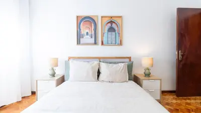 a bedroom with a white bed with two night stands at Bright apartment next metro in Porto