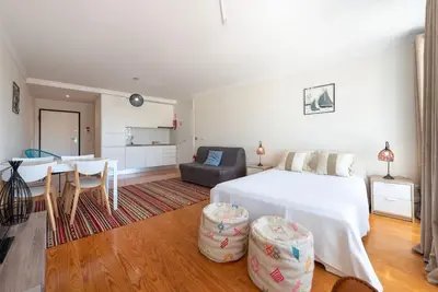 a bedroom with a white bed and a dining room at Cedofeita Studio - Your Porto Escape in Porto