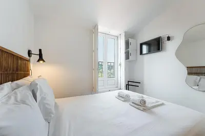 a white bedroom with a large white bed and a window at GuestReady - An urban retreat with river view in Porto
