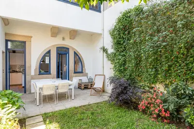 a patio with a table and chairs and a hedge at VIVA Boavista Vintage House in Porto