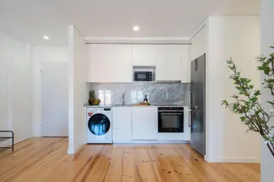 a kitchen with white cabinets and a washing machine at Host Wise - Modern Urban Flat in Porto