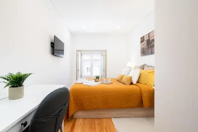 a bedroom with a bed with yellow sheets and a window at Host Wise - Modern Urban Flat in Porto