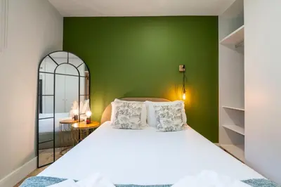 a bedroom with a white bed with a green wall at Casa D'Almeida by Porto Stories in Porto