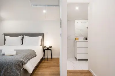 a white bedroom with a bed and a bathroom at GuestReady - Lovely city retreat in Boavista in Porto