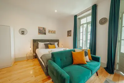 a bedroom with a bed and a green couch at Downtown Suites by Vacationy in Porto
