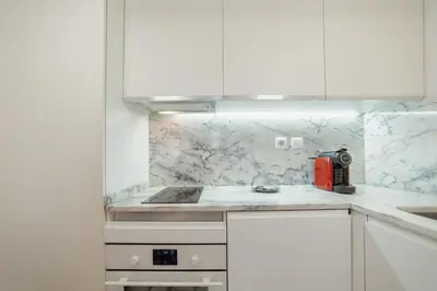 a kitchen with white cabinets and marble counter tops at Downtown Charming by Vacationy in Porto