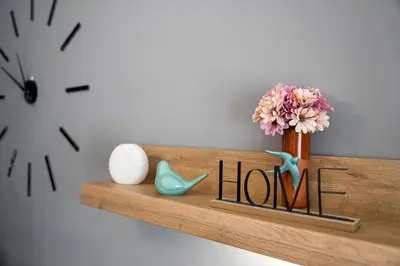 a wooden shelf with a vase of flowers and a clock at Refugio no oPorto in Porto