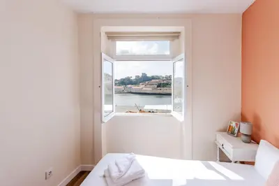 a bedroom with a window with a view of the water at Porto Riverville Apartments in Porto