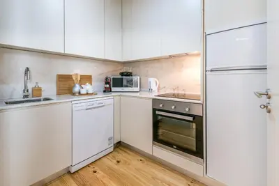 a kitchen with white cabinets and a white refrigerator at GuestReady - Oporto Temptation Apartment in Porto