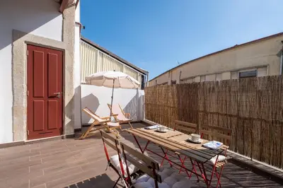 a wooden table and chairs on a balcony with an umbrella at Host Wise - Sunny Downtown Apartment in Porto