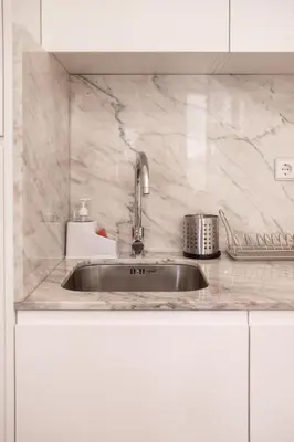 a kitchen with a sink and white cabinets at Host Wise - Sunny Downtown Apartment in Porto