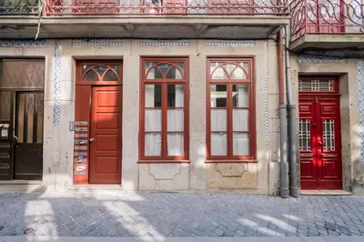 a building with red doors on a street at Host Wise - Sunny Downtown Apartment in Porto