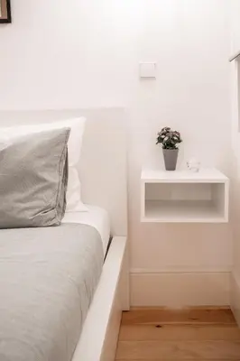 a white bedroom with a bed and a plant on a shelf at Host Wise - Sunny Downtown Apartment in Porto