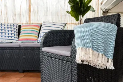 a wicker couch with pillows and a blanket on it at GuestReady - Cosy getaway in Porto in Vila Nova de Gaia