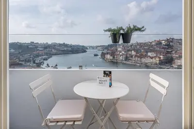 a table and chairs on a balcony with a view of a river at GuestReady - Port Studio 1 in Vila Nova de Gaia