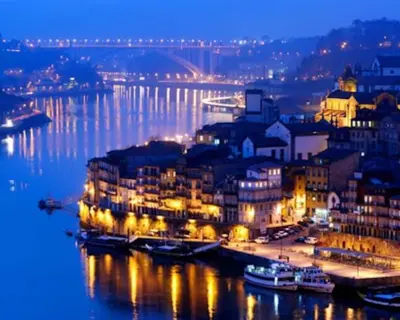 a city lit up at night with boats in the water at GuestReady - Climbing Loft in Porto