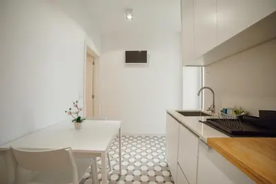 a white kitchen with a sink and a table at Douro Panoramic Views by Vacationy in Porto