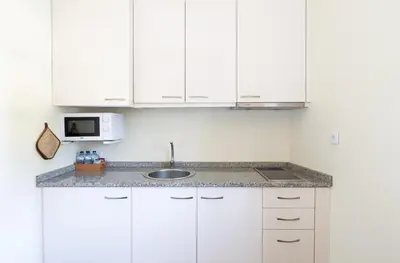 a kitchen with white cabinets and a sink and a microwave at GuestReady - Catorze de Outubro Houses - 387 in Vila Nova de Gaia