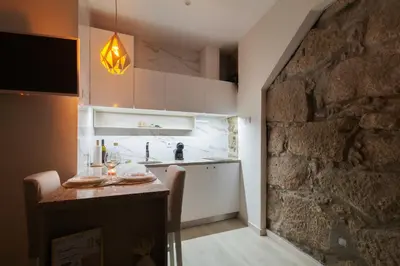 a kitchen with white cabinets and a stone wall at Lady Lapa by Lady Collection in Porto