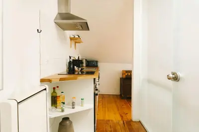a small kitchen with white walls and wooden floors at Studio Faria Guimarães in Porto