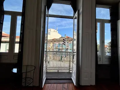 a porch with a table and a chair and an umbrella at Pombeiro Apartments in Porto