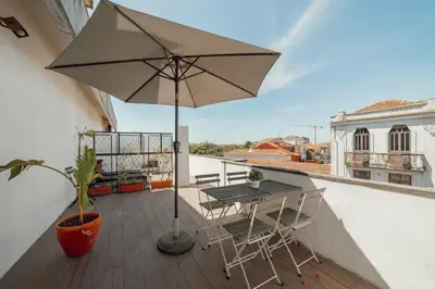 a table and chairs on a balcony with an umbrella at Downtown Classic With Terrace by Vacationy in Porto