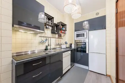a kitchen with black cabinets and white appliances at Woodwork Apartment in Porto