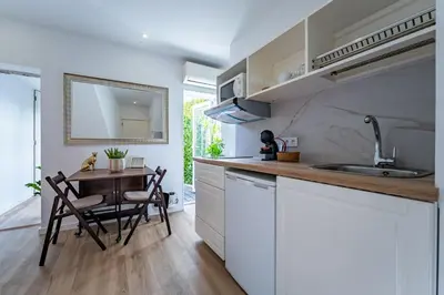 a kitchen with white cabinets and a table and a sink at Oporto Nura Apartment Downtown in Porto