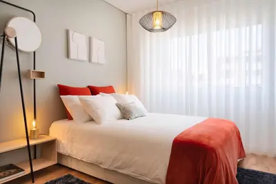 a bedroom with a bed with red pillows and a window at C&P Bolhão Downtown Studio in Porto