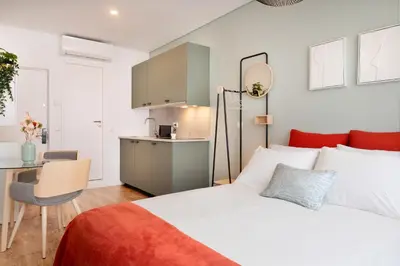 a bedroom with a bed and a small kitchen at C&P Bolhão Downtown Studio in Porto