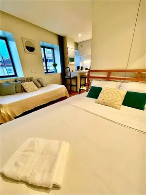 a bedroom with two beds and a kitchen with a table at Cozy Studio in the Heart of Porto in Porto