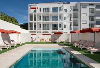 a swimming pool with chairs and umbrellas in front of a building at Vila Catarina Luxury Apartments in Porto