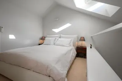 a white bedroom with a bed and a skylight at Dux in Porto