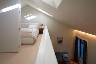 a attic room with a bed and a bedroom with skylights at Dux in Porto