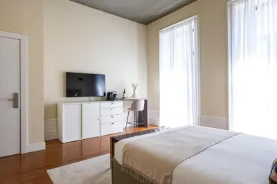 a bedroom with a bed and a flat screen tv at Guesthouse Bonjardim by LovelyStay in Porto