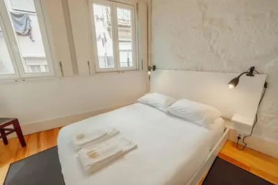 a white bed in a room with two windows at Charming Tiny House by Hosty in Porto