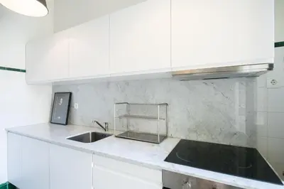 a kitchen with white cabinets and a sink at Baixa24 · City Center Private Sun Deck Apartment in Porto