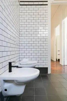a bathroom with two toilets in a white brick wall at Baixa24 · City Center Private Sun Deck Apartment in Porto