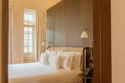 a bedroom with a bed with white pillows and a phone at Palacete Severo in Porto